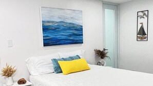 Una camera da letto moderna con un letto grande, un comodino e un quadro appeso al muro, oltre a un elemento decorativo a parete.