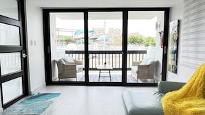 Un soggiorno moderno con un'ampia porta scorrevole in vetro che si apre su un balcone esterno.