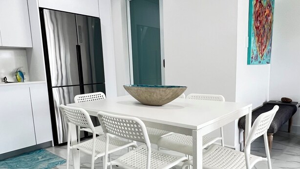 Una cucina moderna con mobili bianchi, un frigorifero in acciaio inossidabile e una porta verde acqua.