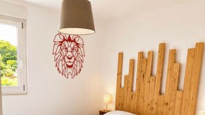 A bedroom with a wooden headboard, a white bedspread, a red abstract wall art, a wooden floor, and a white rug. - Apartments in the Vosges (Fresse-sur-Moselle)
