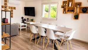 A modern living room with a dining area, a flat-screen TV, wooden shelves, and a large window. - Apartments in the Vosges (Fresse-sur-Moselle)