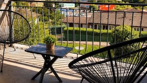 A balcony with a table and chairs, overlooking a rural landscape with houses and greenery. - Apartments in the Vosges (Fresse-sur-Moselle)