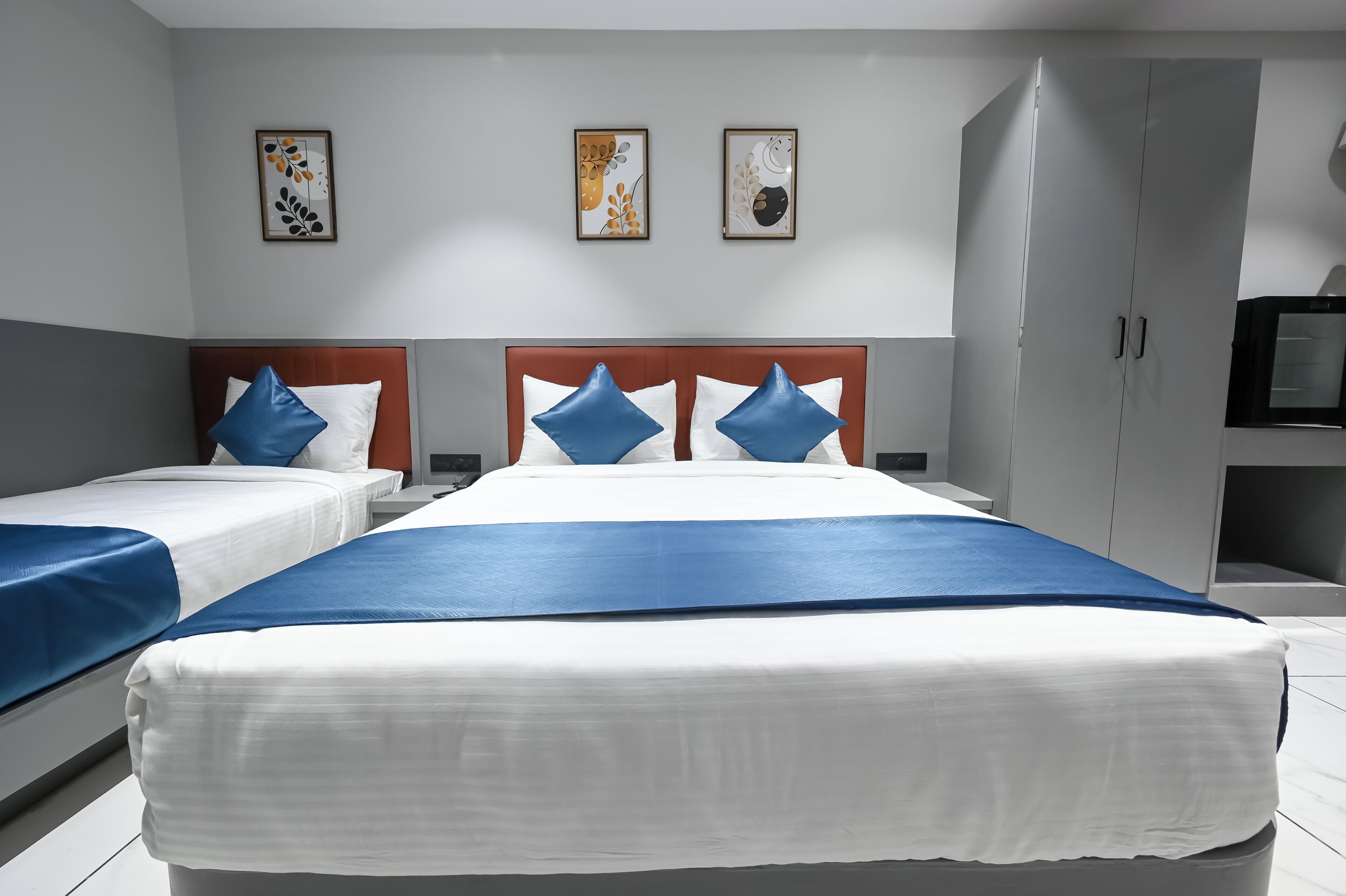 Une chambre d’hôtel avec deux lits, une armoire et un téléviseur.