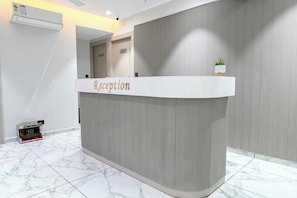 A reception desk with a 'Reception' sign, a security camera, and a plant on top. - Hotel Sun lorem, Ahmedabad (Ahmedabad)