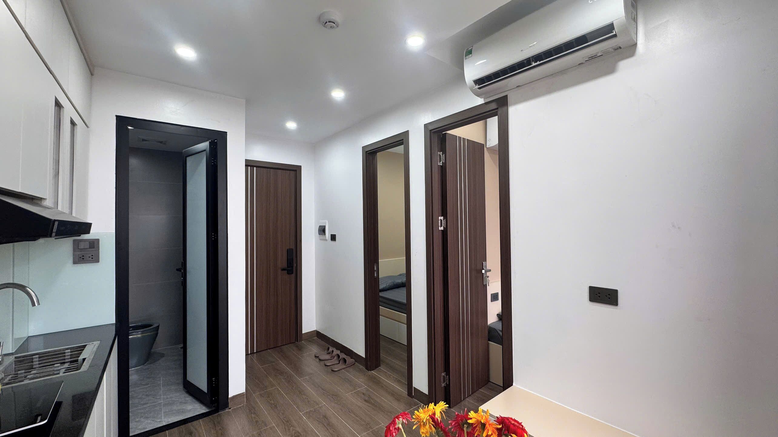 A hallway with a kitchen area on the left, a bed in the middle, and a bathroom on the right.