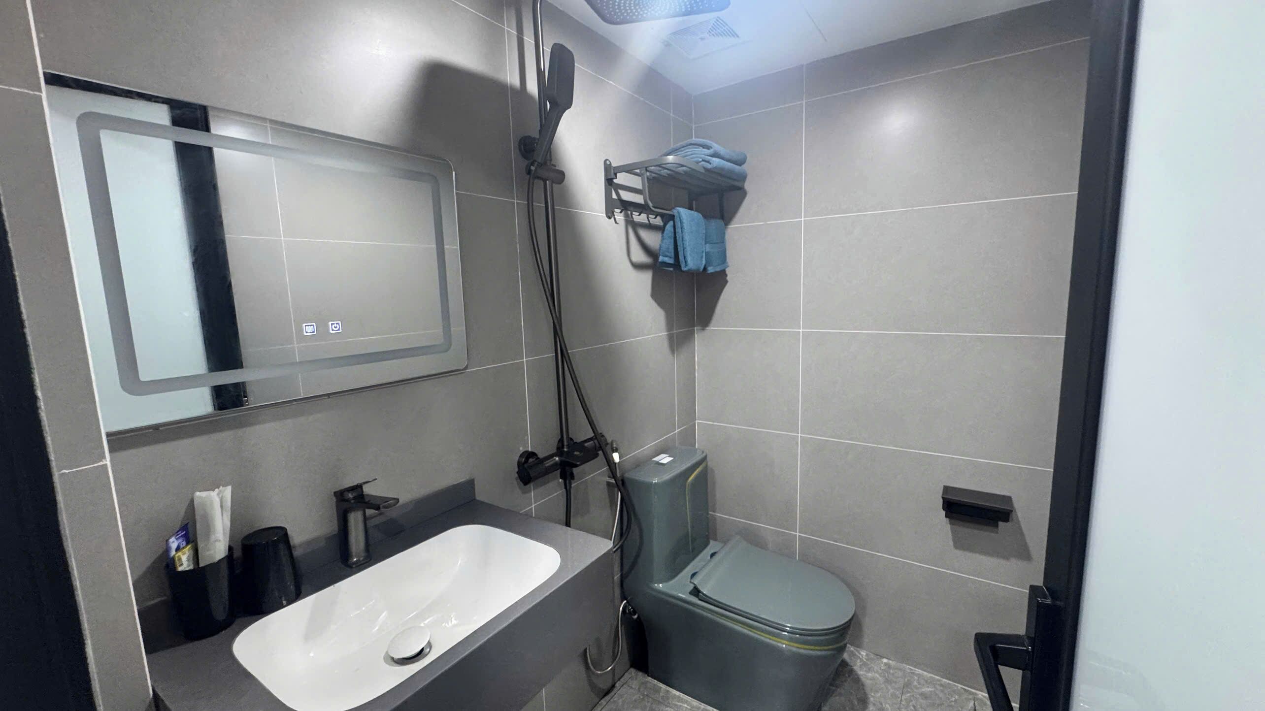 Un baño moderno con un lavamanos blanco, inodoro y ducha.