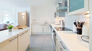 Una cocina moderna con armarios blancos, microondas empotrado y extractor de acero inoxidable.