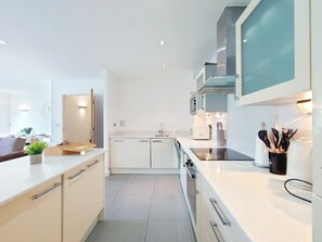 A modern kitchen with white cabinetry, a built-in microwave, and a stainless steel range hood. - Two Bedroom Duplex Pent House in ExCeL (Greater London)