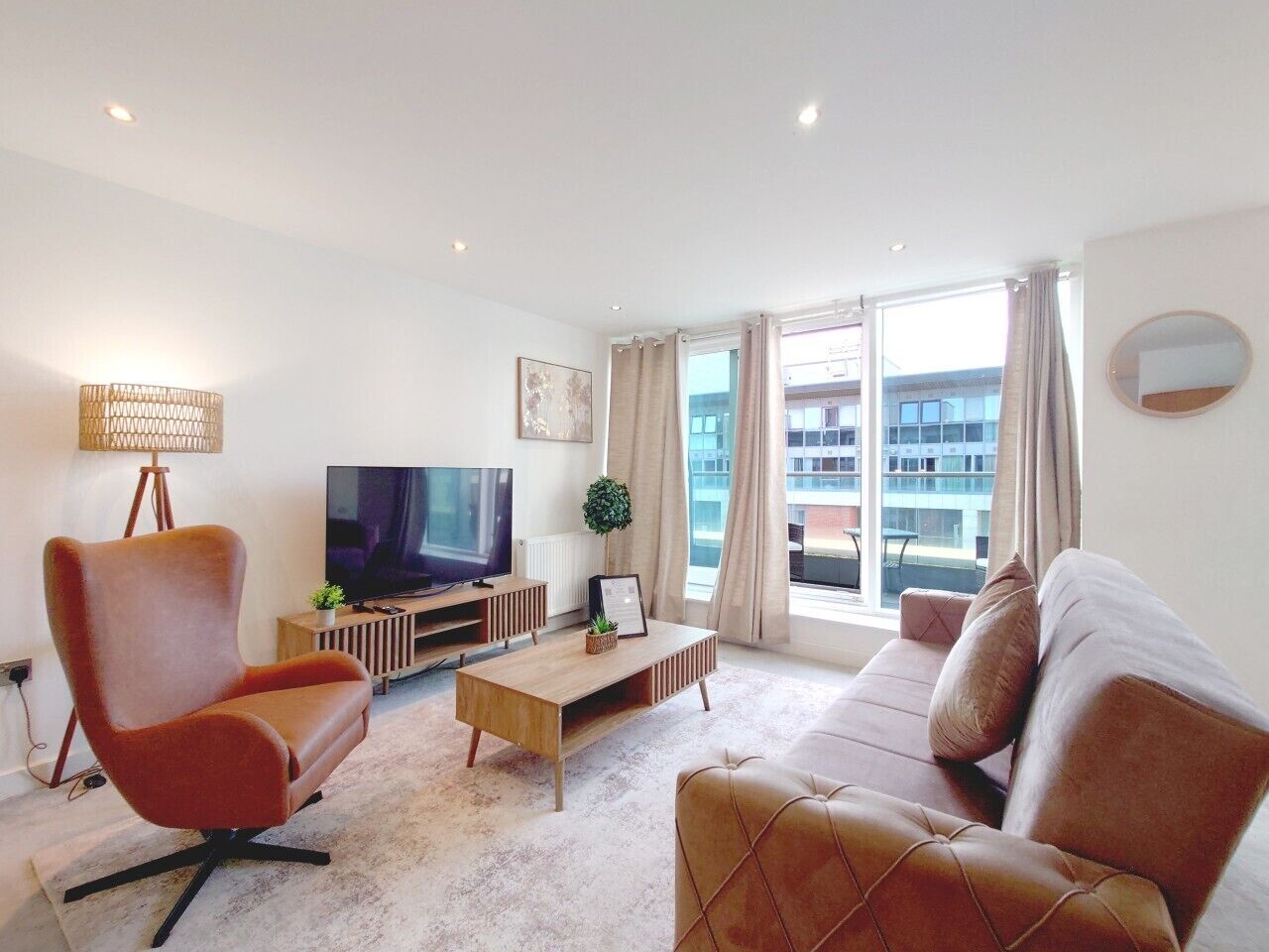 Una sala moderna con sofá, sillón, televisor y mesa de centro.