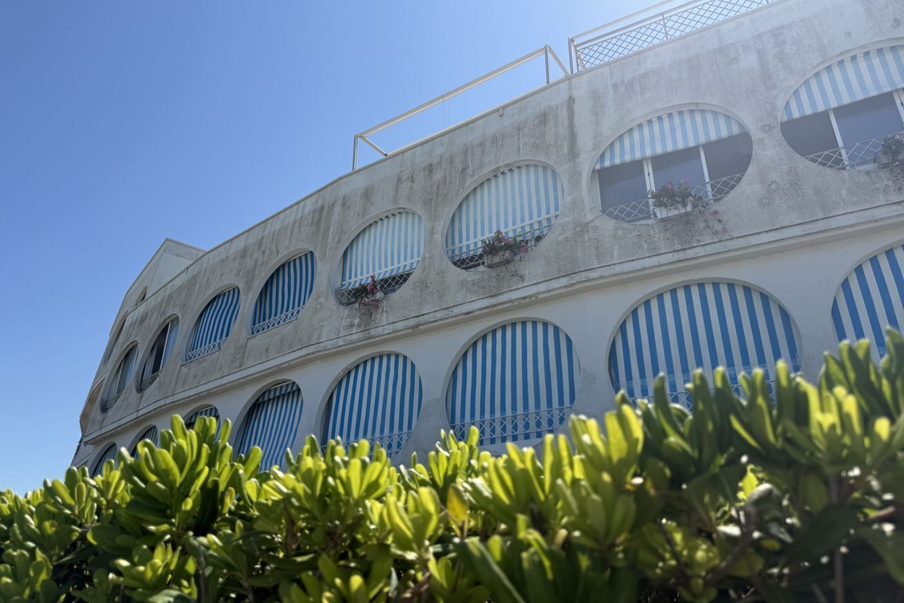 A building with multiple balconies, large windows, and a clear sky.