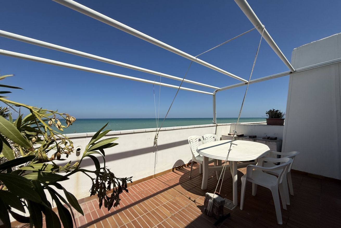 A covered outdoor area with a table and chairs, overlooking a body of water.
