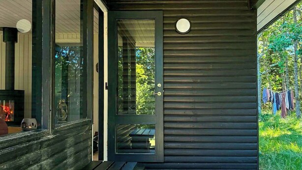 Fachada moderna con un porche cubierto, un banco de madera y una chimenea decorativa.
