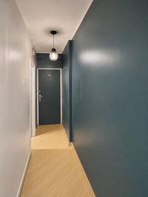 A hallway with a wooden floor, a dark blue wall, and a door with a light switch. - Furnished apartment with garage and Wi-Fi in Santa Cecília – São Paulo (São Paulo)
