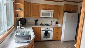 A kitchen with wooden cabinets, a microwave, a refrigerator, a sink with a faucet, and a stove.
