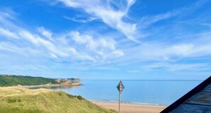 A coastal landscape with a clear sky, a beach, and a signpost. - Luxury Clifftop Beach House: Panoramic Sea Views, FREE Hot Tub & Games Room (Cayton Bay)