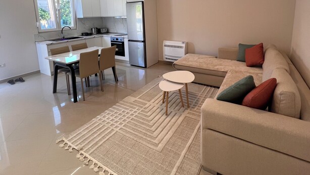 Ein modernes Wohnzimmer mit einer Couch, einem Esstisch und einer Küche im Hintergrund.