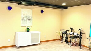 A room with a white cabinet, a painting on the wall, and a drum set. - Northwest Elegance – Modern Retreat (Normandy Park)