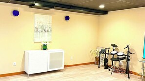 A room with a white cabinet, a painting on the wall, and a drum set. - Northwest Elegance – Modern Retreat (Normandy Park)