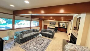 A living room with two sofas, a coffee table, and a rug. There is a kitchen area in the background. - Northwest Elegance – Modern Retreat (Normandy Park)