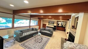 A living room with two sofas, a coffee table, and a rug. There is a kitchen area in the background. - Northwest Elegance – Modern Retreat (Normandy Park)