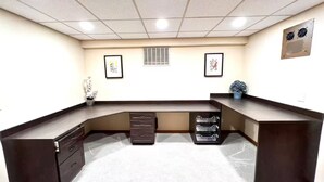 A reception desk with a dark finish, a white tiled ceiling, and framed artwork on the walls. - Northwest Elegance – Modern Retreat (Normandy Park)