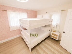A bunk bed with a bedside table and lamp, a door, and a window with curtains. - Modern Home w Pool / Jaccuzi / Game Room - 8PPL (Seminole)
