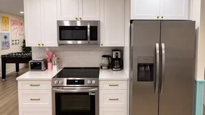 Una cucina moderna con mobili bianchi, elettrodomestici in acciaio inossidabile e pavimento in legno.