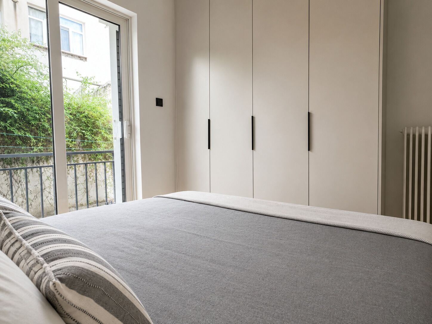 Een slaapkamer met een bed, een kledingkast en een radiator.
