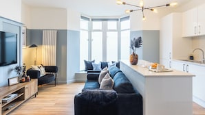 Ett modernt vardagsrum med en soffa, en tv och en matplats med en köksö.