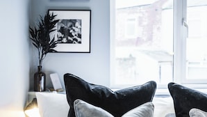 Ett sovrum med en säng, kuddar, ett nattduksbord, en lampa, inramade bilder på väggen och ett fönster med utsikt.