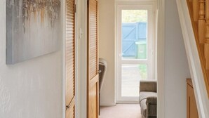 Ein Flur mit einer Holztreppe, einer Tür zu einem Zimmer und Blick ins Freie.