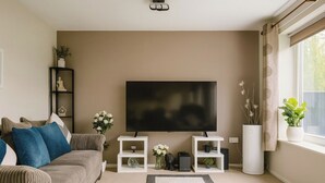 Ein Wohnzimmer mit einem großen Flachbildfernseher, einem Sofa, einem Couchtisch und Dekorationselementen.