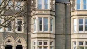 Un bâtiment historique doté d’une tourelle d’angle, de grandes baies vitrées et d’une façade en pierre.