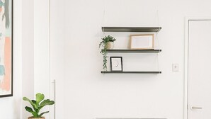 Une chambre à coucher comprenant un lit, une commode, un radiateur et des étagères murales décorées de divers objets.