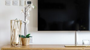 A wooden entertainment center with a flat-screen TV mounted above it. - The Riverside Haven – City Centre + Parking (Newport)