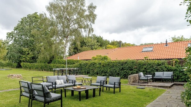 Eine Terrasse mit Gartenmöbeln, ein Kiesweg und ein Haus mit einem Ziegeldach.