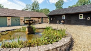 Ein Innenhof mit einem Brunnen, Steinmauern und einem Holzgebäude, vor dem ein Fahrrad steht.