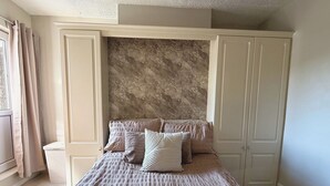 Ein Schlafzimmer mit einem Bett, einer Wand mit Marmormuster und einem Kleiderschrank.
