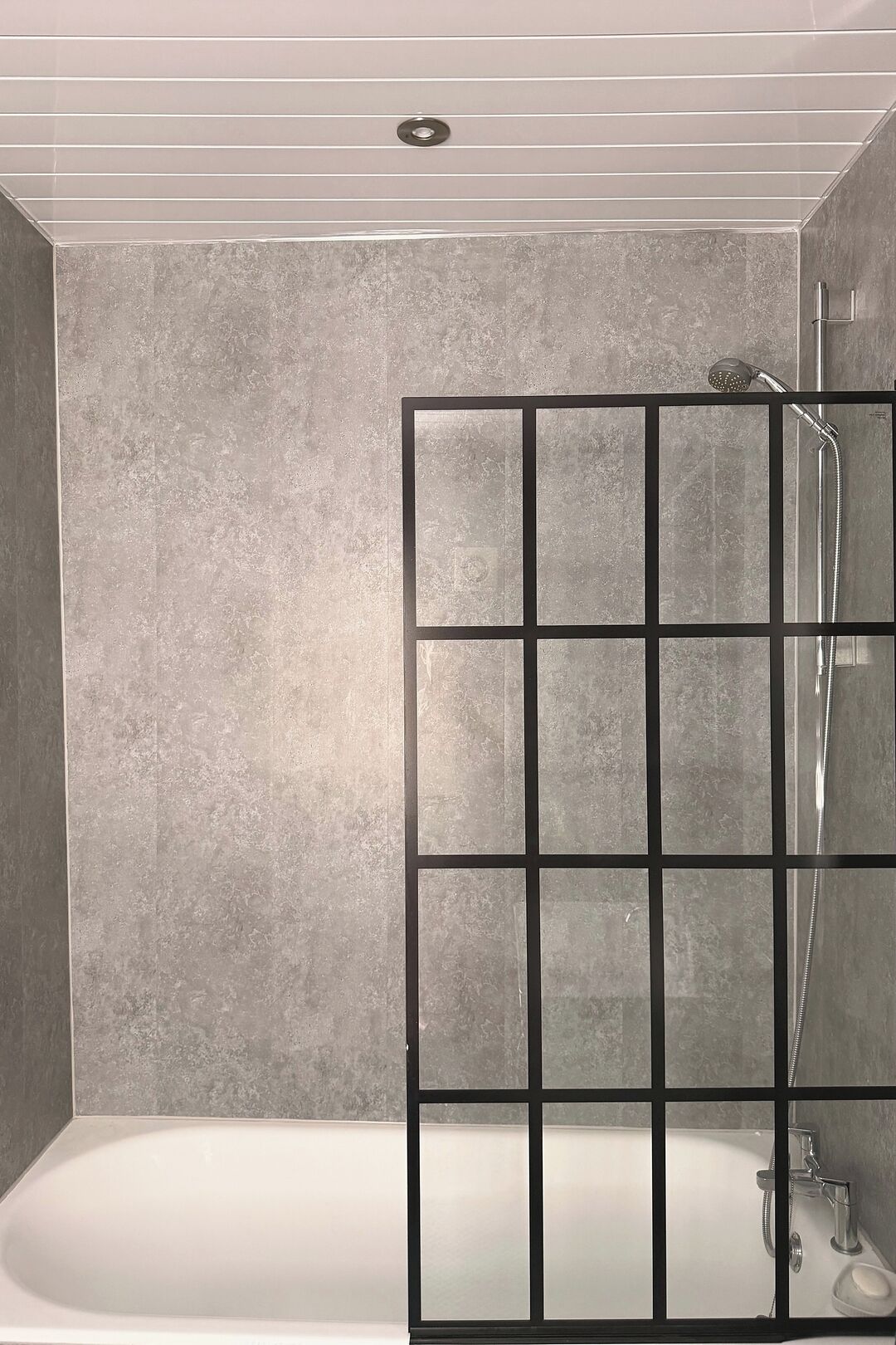 A bathroom with a bathtub, a shower with a glass partition, and a tiled wall.