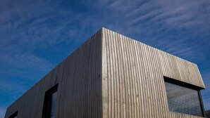 Un edificio moderno caratterizzato da listelli verticali in legno e un'ampia vetrata.