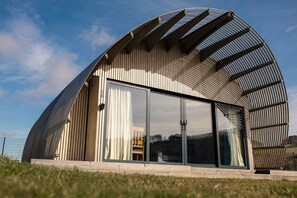 A modern building with a curved roof, large glass windows, and a wooden exterior. - Lost Shore Surf Resort (Newbridge)
