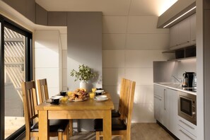 A compact kitchen with a dining area, equipped with modern appliances and a breakfast setup. - Lost Shore Surf Resort (Newbridge)