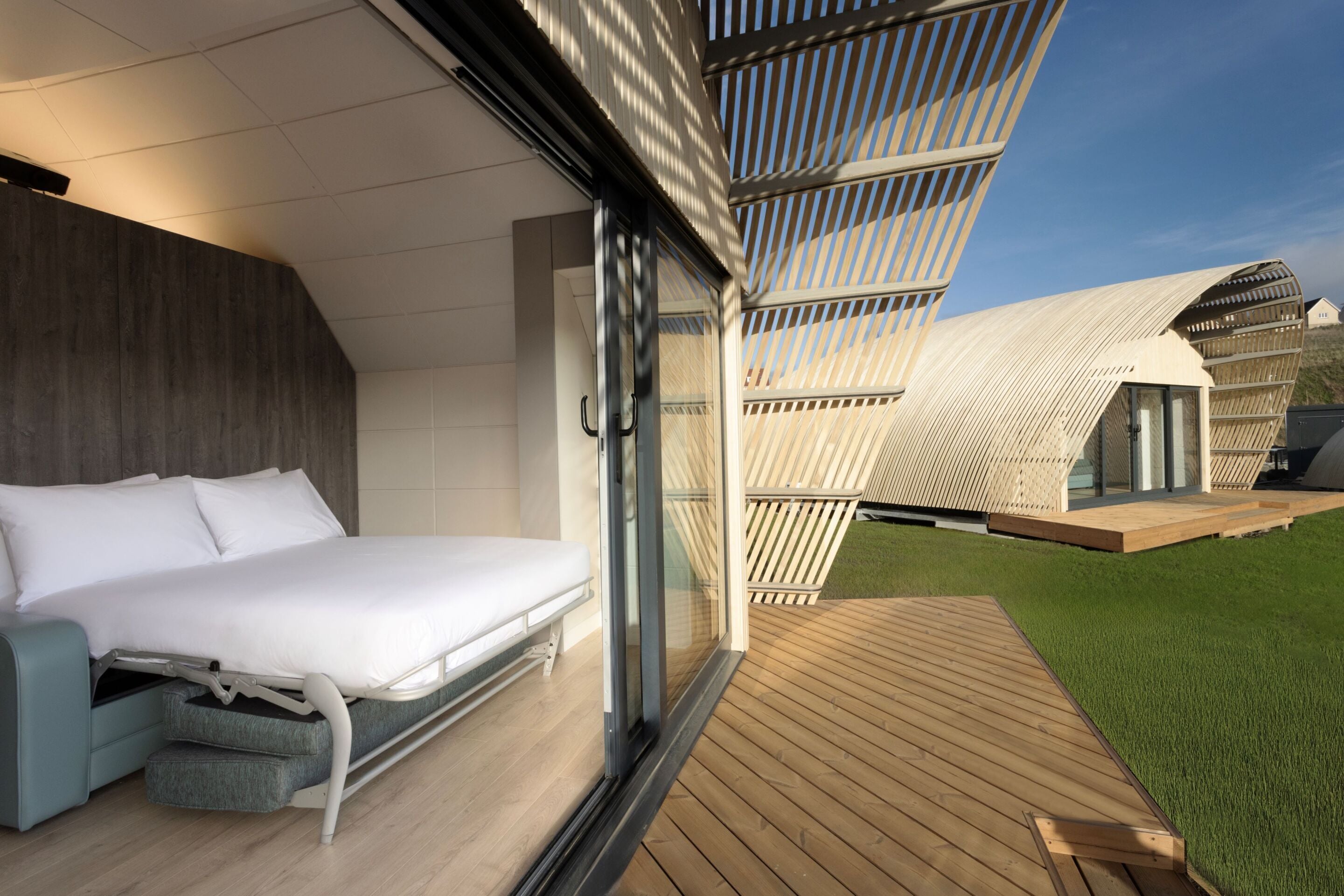 A modern bedroom with a bed, a seating area, and a view of a unique architectural structure.