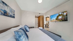 A hotel room with a bed, a television, and a painting on the wall. - Luxury 2BR | Downtown Miami Condo | Rooftop Pool (Miami)
