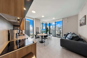A modern apartment with a kitchen, dining area, and living room, featuring large windows with a city view. - Luxury 2BR | Downtown Miami Condo | Rooftop Pool (Miami)
