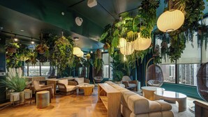 A modern lounge with wooden flooring, comfortable seating, hanging plants, and large windows offering city views. - Luxury 2BR | Downtown Miami Condo | Rooftop Pool (Miami)