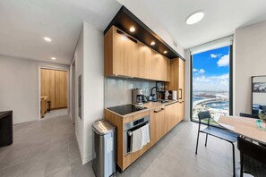A modern kitchen with wooden cabinets, a stainless steel sink, and a view of a marina through large windows. - Luxury 2BR | Downtown Miami Condo | Rooftop Pool (Miami)
