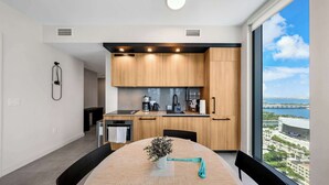 A modern kitchen with wooden cabinets, a coffee maker, and a view of the city. - Luxury 2BR | Downtown Miami Condo | Rooftop Pool (Miami)