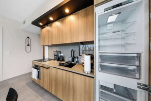 A modern kitchen with wooden cabinets, a built-in oven, and a coffee machine. - Luxury 2BR | Downtown Miami Condo | Rooftop Pool (Miami)