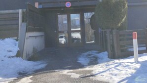 En byggnad med flera våningar, en grind vid ingången, en skylt som förbjuder parkering och en snötäckt mark.